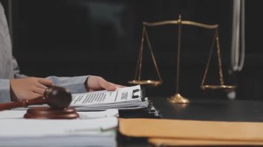Avukat, büro masasında dokümanlar ve terazilerle, adalet ve yasal belgelerle, hukuk hizmetleri ve hukuk kavramlarıyla çalışıyor. Avukat, evraklarla uğraşıyor.