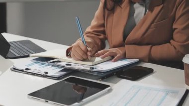 İş kadını masanın üzerine bir defter yazıyor.