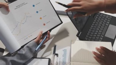 Ofis masasında bilgisayar ve mali raporlarla çalışan iş adamları