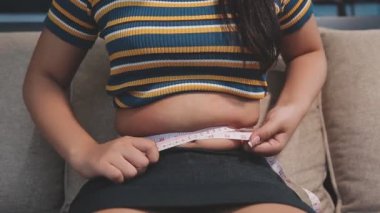 Şişman karnını mezurayla ölçen bir kadın.