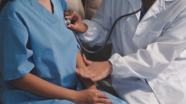 Steteskoplu bir doktor bir hastayı hastanede tutuyor.