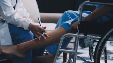 Steteskoplu kadın doktor ve ofiste tekerlekli sandalyede genç bir adam.