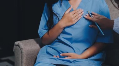 Hastanedeyken mavi üniformalı doktor hastanın elini tutuyor.