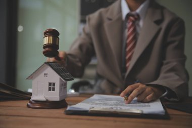 Emlak Hukuku, Ev Sigortası, Emlak Vergisi, Açık Artırma ve Açık Artırma Konsepti. Adliyedeki masasında tokmak adalet çekici olan küçük oyuncak ev modeli..