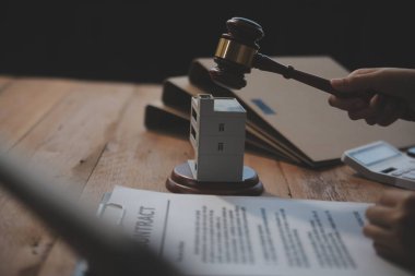 Emlak Hukuku, Ev Sigortası, Emlak Vergisi, Açık Artırma ve Açık Artırma Konsepti. Adliyedeki masasında tokmak adalet çekici olan küçük oyuncak ev modeli..