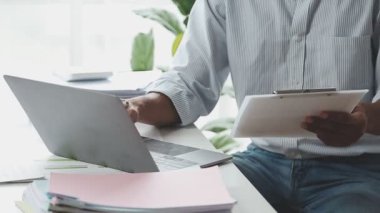 Genç adam dizüstü bilgisayarını elinde tutuyor..