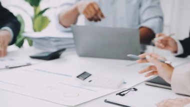 Bir grup iş adamı, bir ofisteki toplantıda fikir alışverişinde bulunuyorlar.