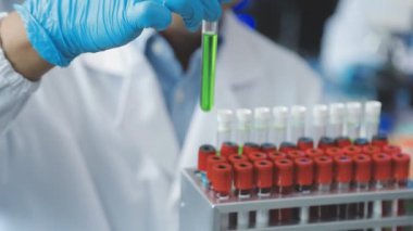 Koruyucu kıyafetli erkek doktor laboratuarda test tüpüyle çalışıyor.