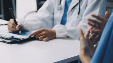 Kadın doktor el ele tutuşup bir şey gösteriyor.