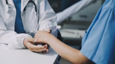 Yakın plan - genç bir hastanın elini tutan doktor.