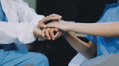 Doktorlar ve hemşireler tıbbi bir ekipte el ele tutuşuyorlar.
