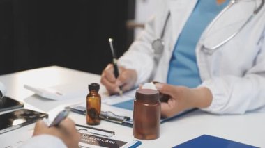 Doktor elinde hap ve ilaç şişesi tutuyor.