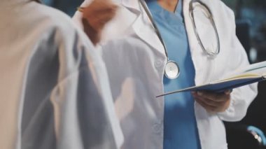 Hastanenin arka planında steteskop ve hasta tutan bir doktor eli var..