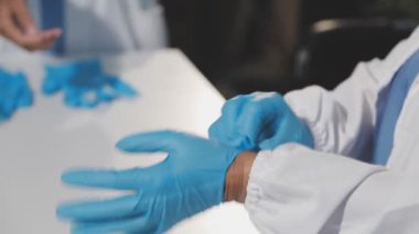 Beyaz eldivenli ve lateks eldivenli doktor el ele tutuşuyor.