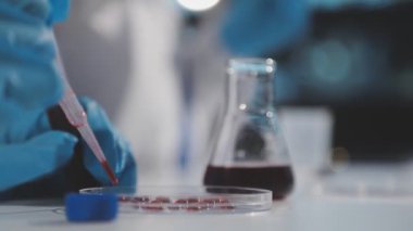 Mavi üniformalı, kırmızı tüplü bir laboratuvar asistanı.