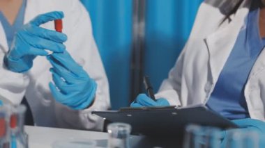 Laboratuvar asistanı elinde kan örneğiyle test tüpü tutuyor..