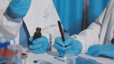 Laboratuvarda elinde bir tüp sıvı tutan bilim adamının yakın çekimi.