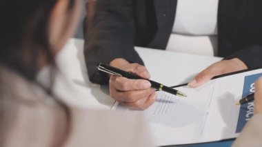 Ofisteki toplantıda bir kadın eli kalem ve bir belgeyle kapatılıyor.