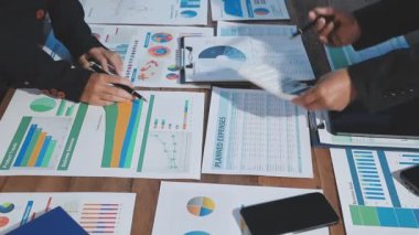 İş adamı elinde hesap makinesi, kalem ve finansal çizelgeyi ahşap masada tutuyor..