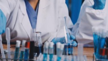 Yakın plan - mavi ceketli bir bilim adamının kimya laboratuvarında çalışması.