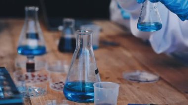 Mavi takım elbiseli bilim adamı ve test tüpü tutan gözlüklü bilim adamı ve kimyasal laboratuarda sıvı..