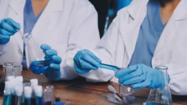 Yakın çekim - mavi labaratuvar eldivenleri ve laboratuarda test tüpü tutan koruyucu tıbbi eldivenler