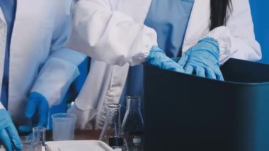 Laboratuvarda sıvı tüpü tutan koruyucu eldivenler giyen bilim adamı.