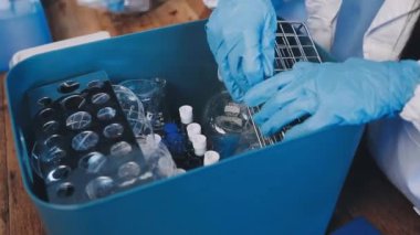 Bilim adamı elinde mavi bir sıvıyla plastik bir kap tutuyor.
