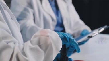 Bilim adamının elinde bir tablet kalem ve tüp tutarken yakın plan.