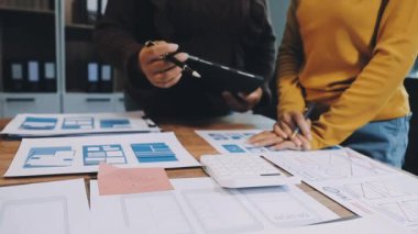 Sıradan giyinen genç adam ofiste tabletle çalışıyor.