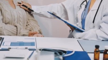 Genç bayan doktor ofisinde yaşlı bir hasta için reçete yazıyor..