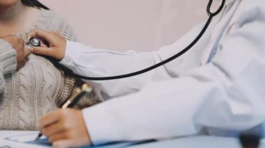 Yaşlı bir hastanın vücut ısısını ölçen doktor.