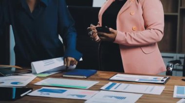 Genç iş kadını belgeyi tutuyor ve modern ofiste çalışan ekibiyle mali raporları tartışıyor..