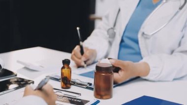 Genç kadın doktor elinde haplar ve bir şişe su tutuyor.