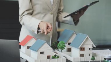 Emlakçı, masanda model ev modeli ve model ev modeli tutuyor. Emlak kavramı