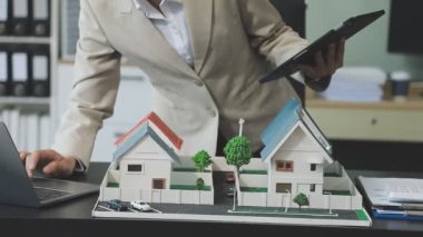 Minyatür evi olan bir adam ve arka planda bir model.