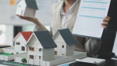 Emlakçı ev modelini alıp almak için gösteriyor.