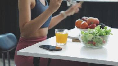 Genç bir kadın mutfakta salata yiyor.