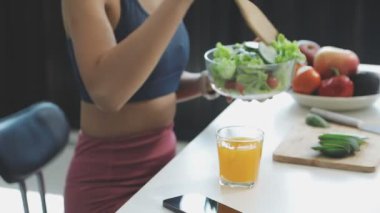 Genç bir kadın mutfakta sağlıklı sebze salatası yiyor.