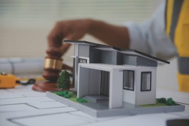 Yargıç Gavin, arka planda sarı bir kaskla bina planları hazırlıyor. İnşaat ve mühendislikle ilgili konularla ilgili yasalar. İnşaat hukuku kavramı.