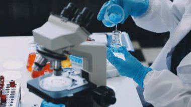 Laboratuvarda koruyucu eldivenli bir bilim adamı matarayı tutuyor. Kapat - kapat