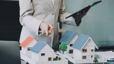 İş adamı arka planda model ev modelini tutuyor