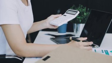 İş kadını harcamaları hesaplamak için cep telefonu ve hesap makinesi kullanıyor.