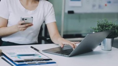 Akıllı telefon kullanan ve dizüstü bilgisayarda yazan iş kadını.