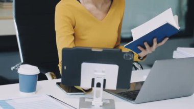 Modern ofiste dizüstü bilgisayar kullanan genç bir kadın.