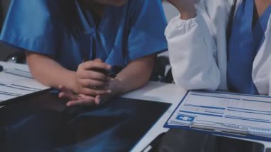 İki doktor hastane odasında sağlık raporunu tartışıyor.