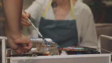 Sanatçının elinde palet ve fırçayla bir palet tutarken