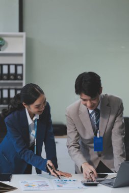 Ofiste dizüstü bilgisayar kullanan neşeli iş adamları. Modern bir çalışma alanında birlikte çalışırken gülümseyen genç girişimciler. Masada birlikte oturan iki genç iş adamı..