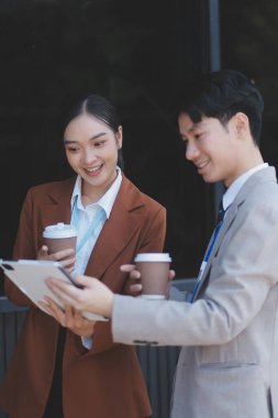 Başarılı genç iş adamları modern iş binası önünde konuşuyor, birlikte çalışıyorlar.