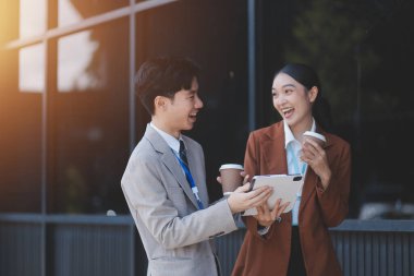 Başarılı genç iş adamları modern iş binası önünde konuşuyor, birlikte çalışıyorlar.